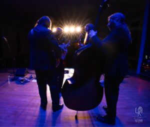 String Quartet Stage Performance Musicians playing string instruments on stage with spotlight effects and musical equipment.
