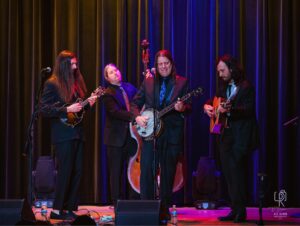 String Quartet on Stage Musicians in suits perform on stage with mandolin, double bass, banjo, guitar, colorful lighting.