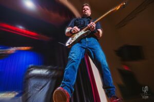 Energetic Guitar Performance on Stage Musician playing electric guitar on stage; dynamic low-angle view with blurred background.