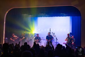 Celtic Band Live Performance Band Skerryvore performs live with colorful lights, featuring bagpipes, guitar, violin, and accordion.