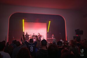 Skerryvore Live Performance Band Skerryvore performs on stage with red lighting, violin, keyboard, and engaged audience.