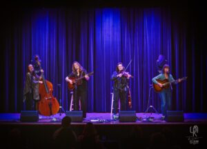 String Quartet Live on Stage Musicians on stage with blue curtain, playing double bass, guitars, violin; live concert setup.